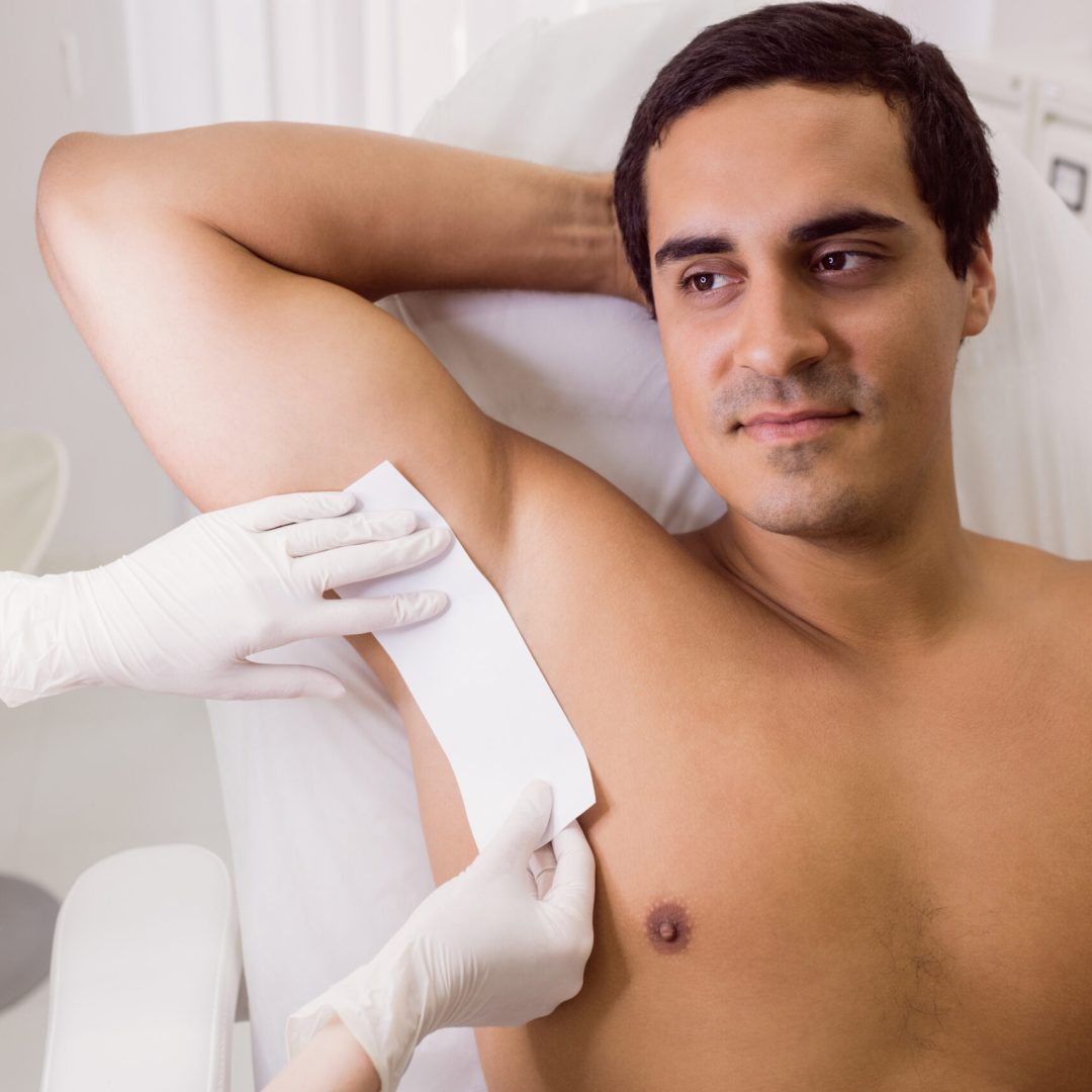 Doctor waxing male patient skin in clinic